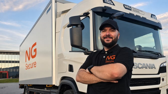 NG Secure-sjåfør med caps og svart t-skjorte med NGS-logo foran hvit kassebil med NGS-logo.